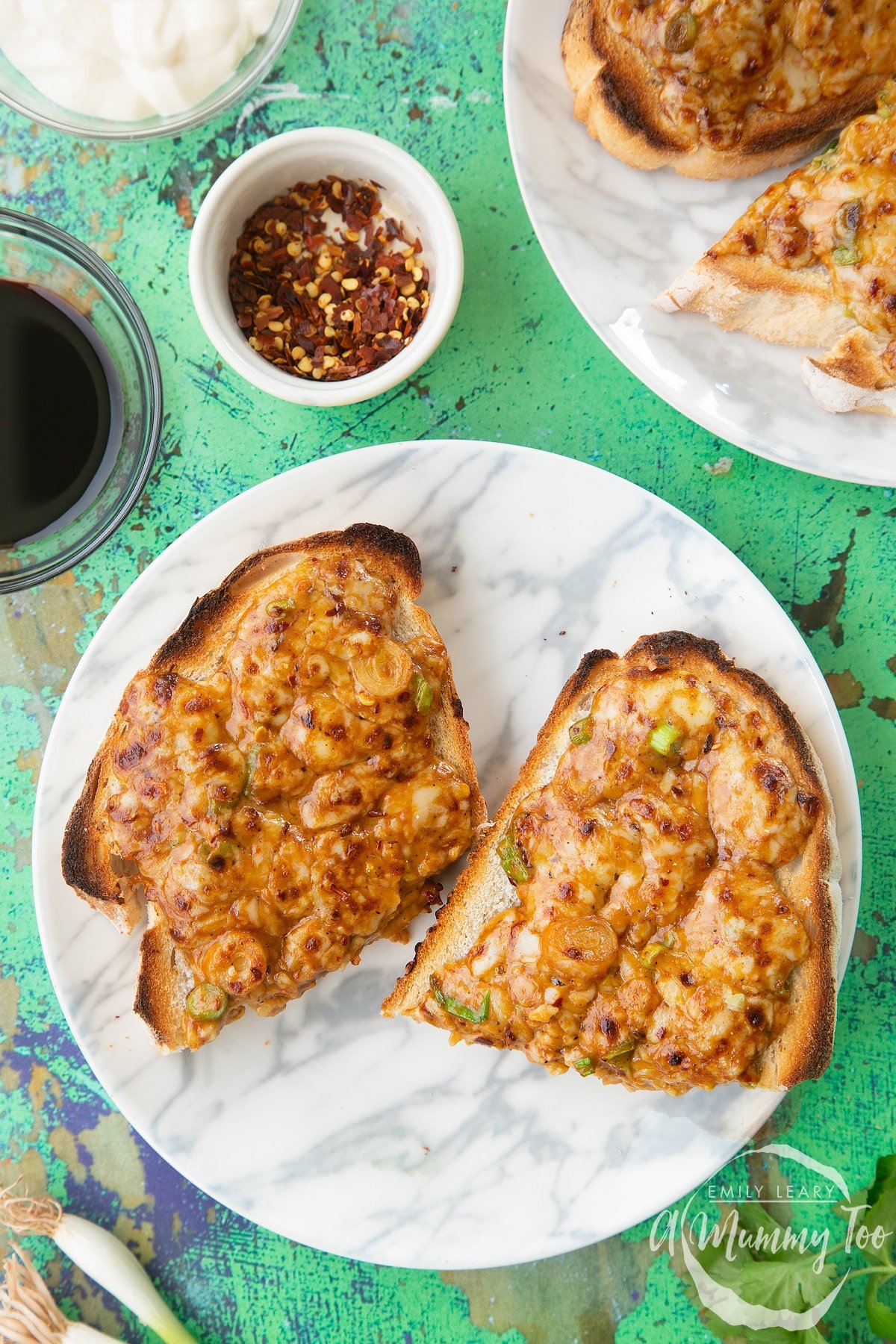 Two pieces of chilli cheese toast  on a white marbled plate. 