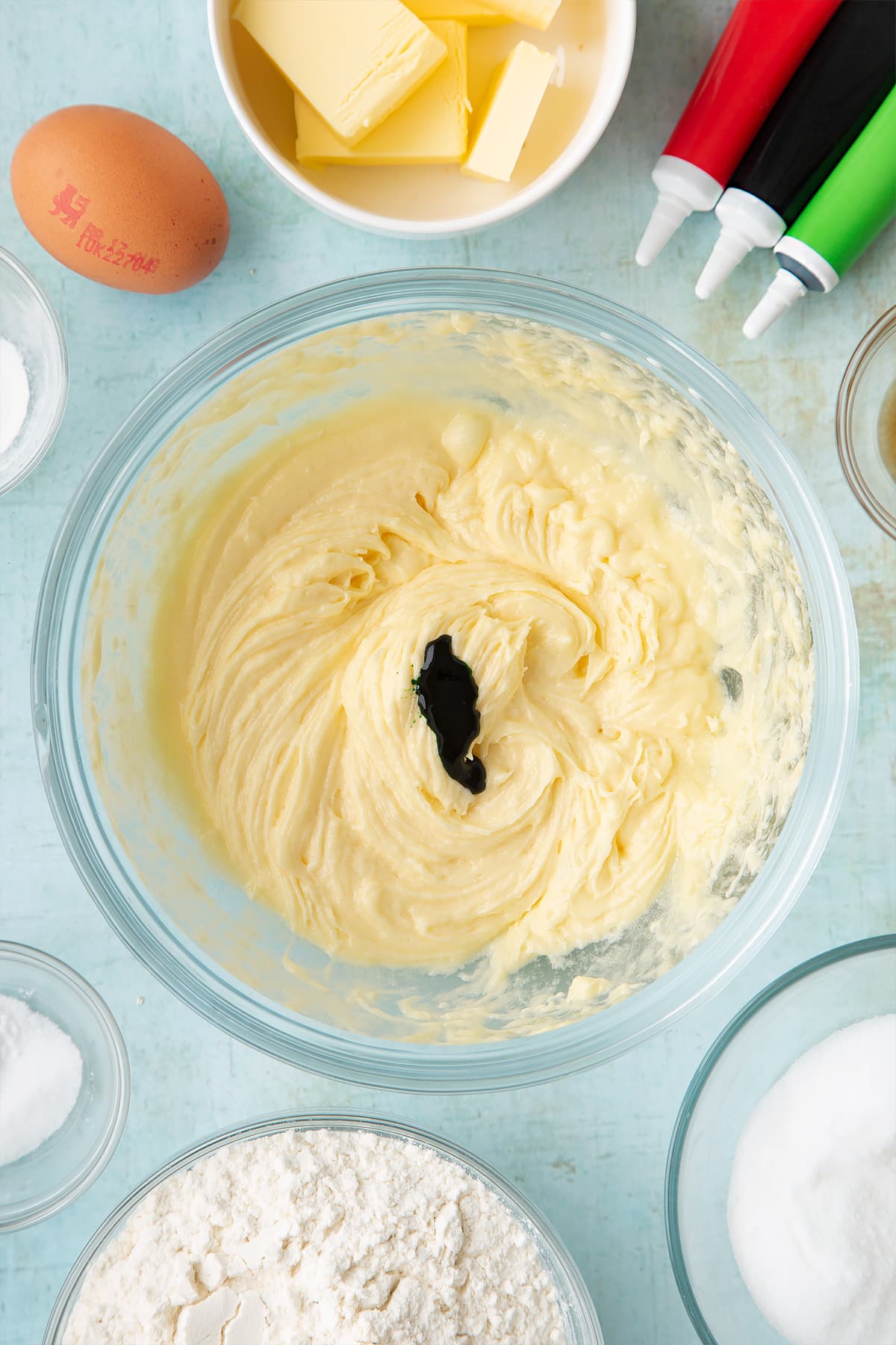 Overhead shot of butter mix with green food colouring in a clear bowl