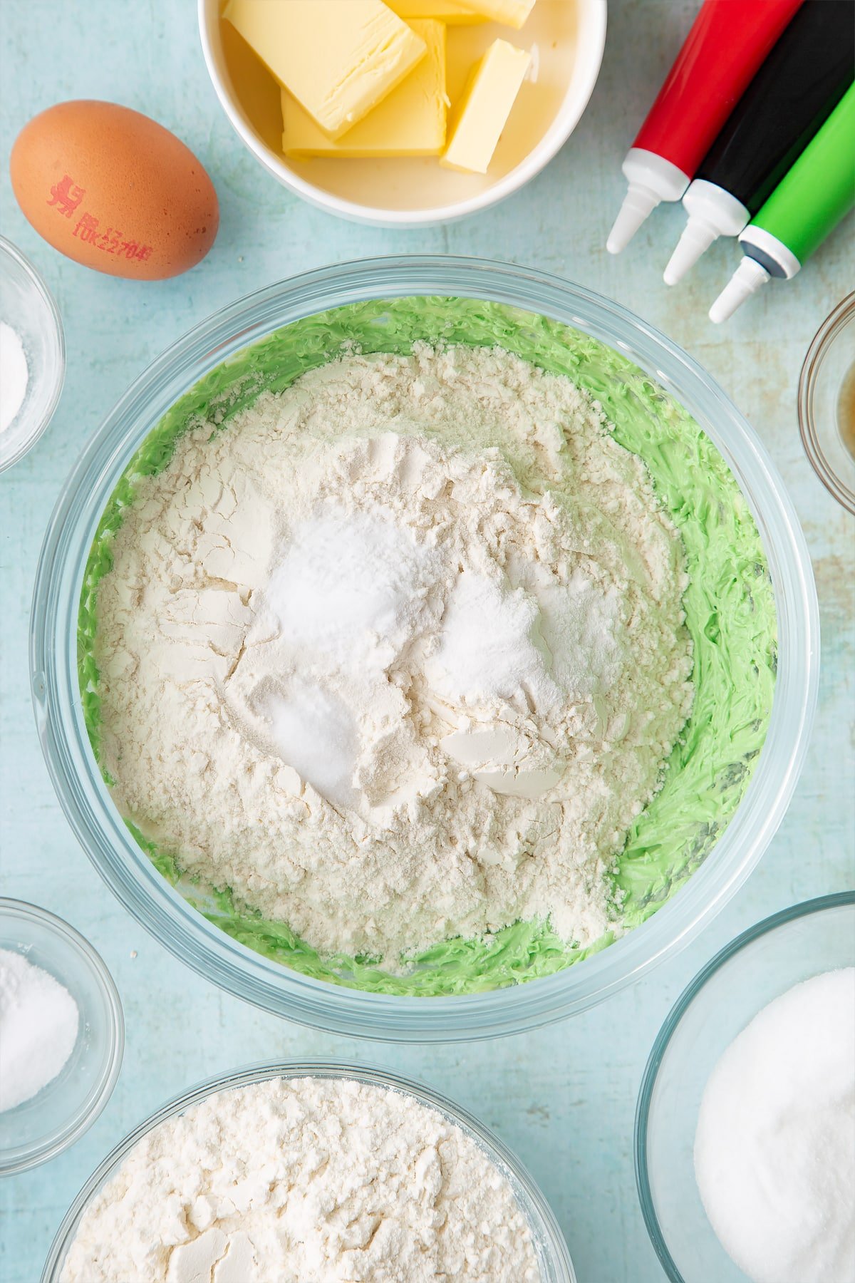 Overhead shot of flour, baking powder, salt and bicarbonate of soda in a large clear bowl