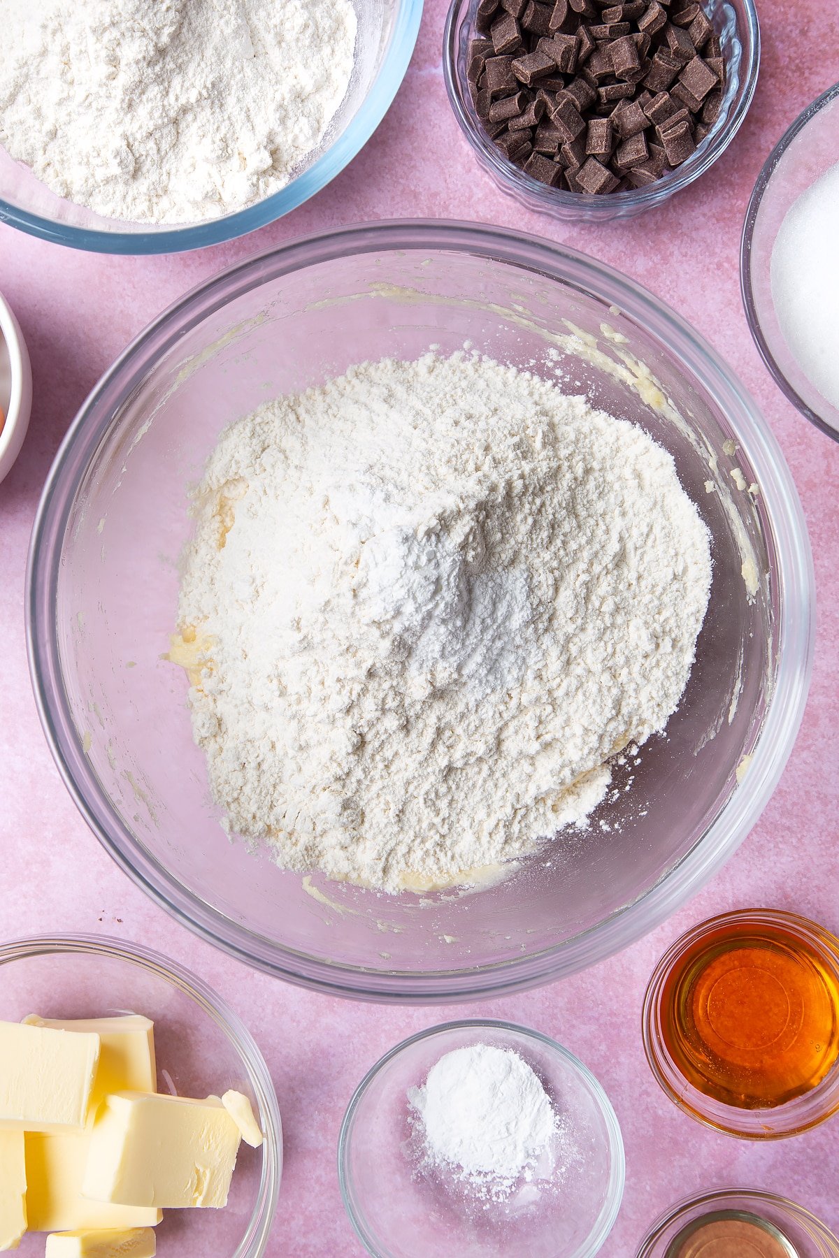 Overhead shot of butter, flour and baking powder in a large clear bowl