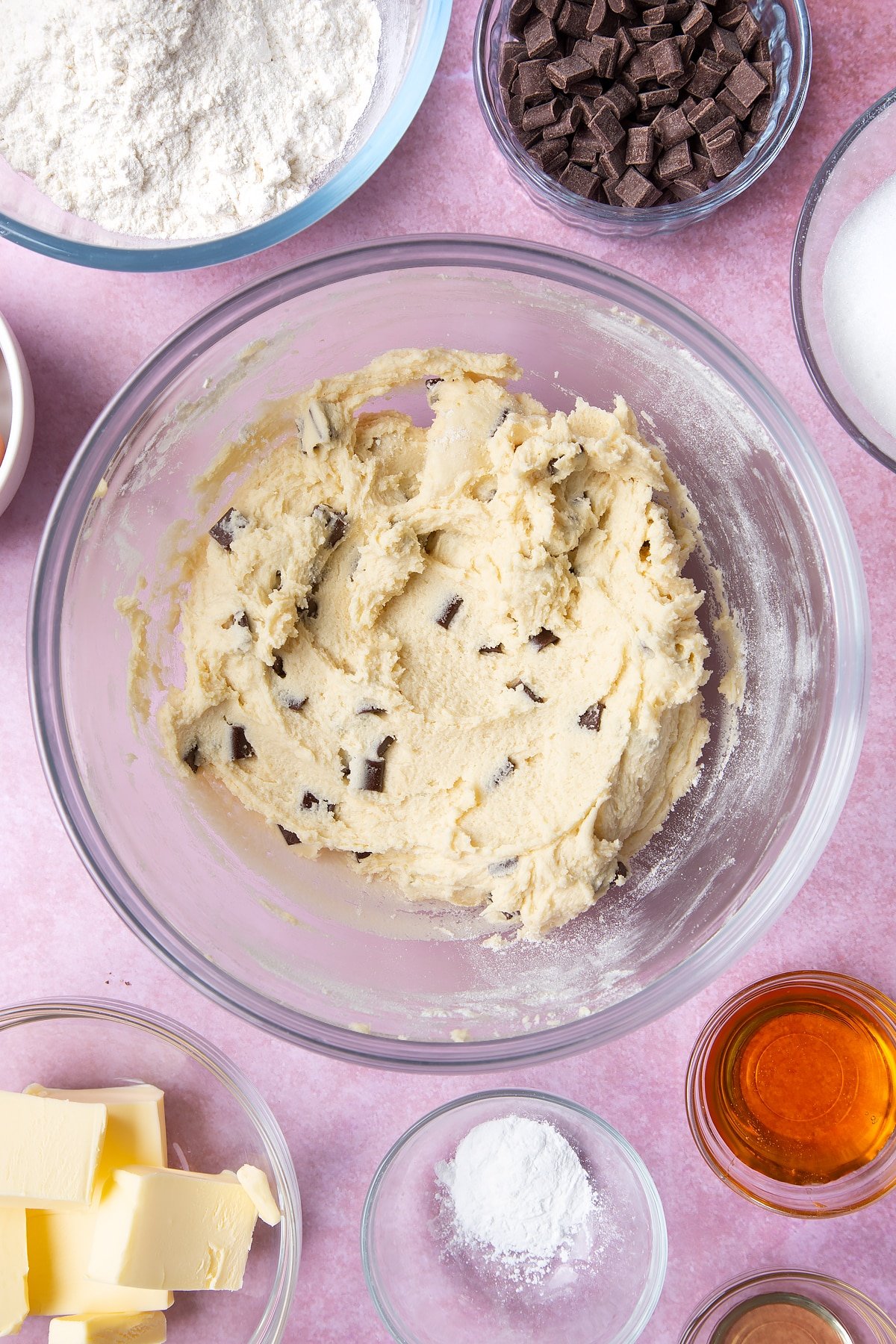 Overhead shot of fluffed butter and other ingredients for the chocolate chip cookies in a large clear bowl