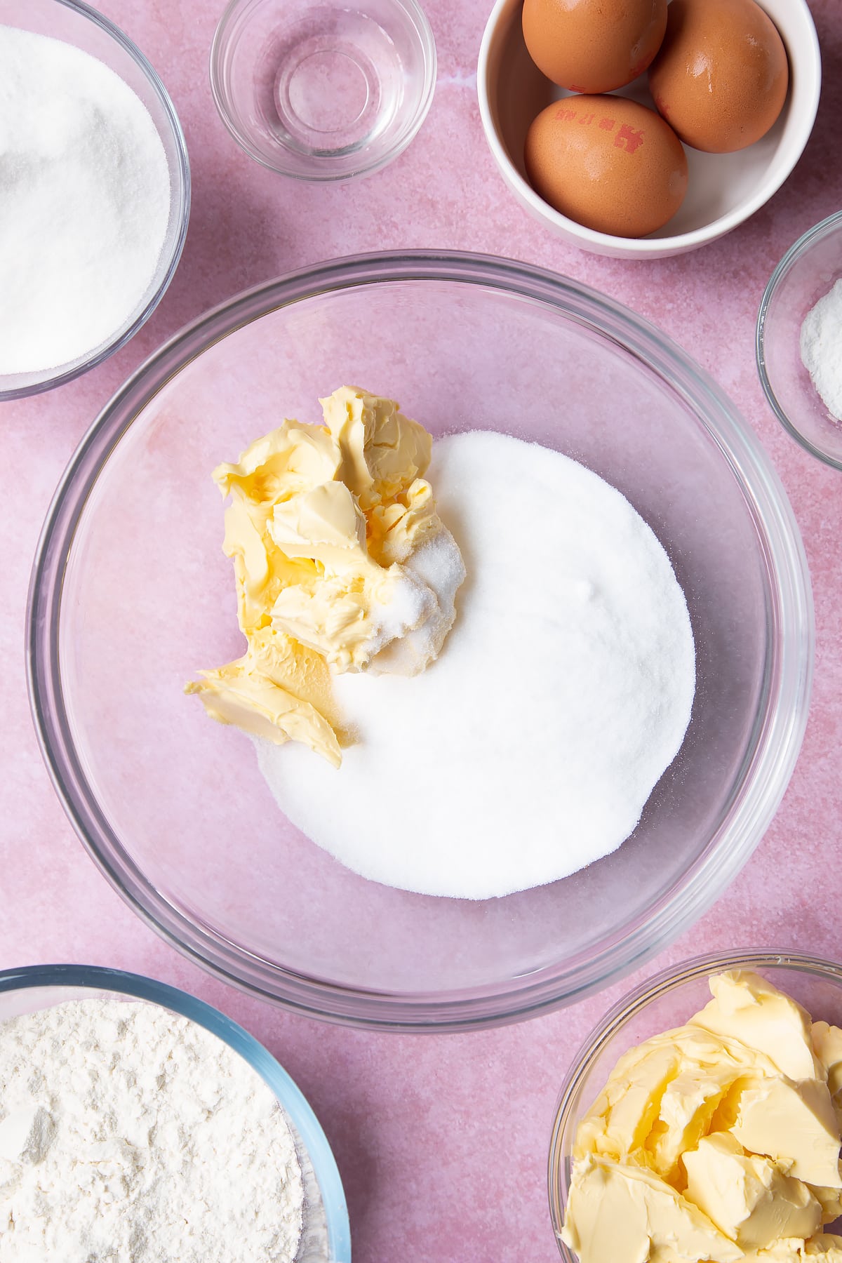 Overhead shot of margarine and sugar in a clear mixing bowl