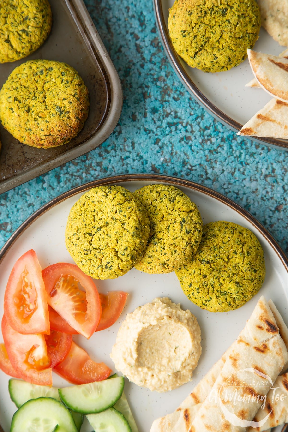 Gluten-free falafel on a plate with tomatoes, cucumber, hummus and griddled flatbread. 