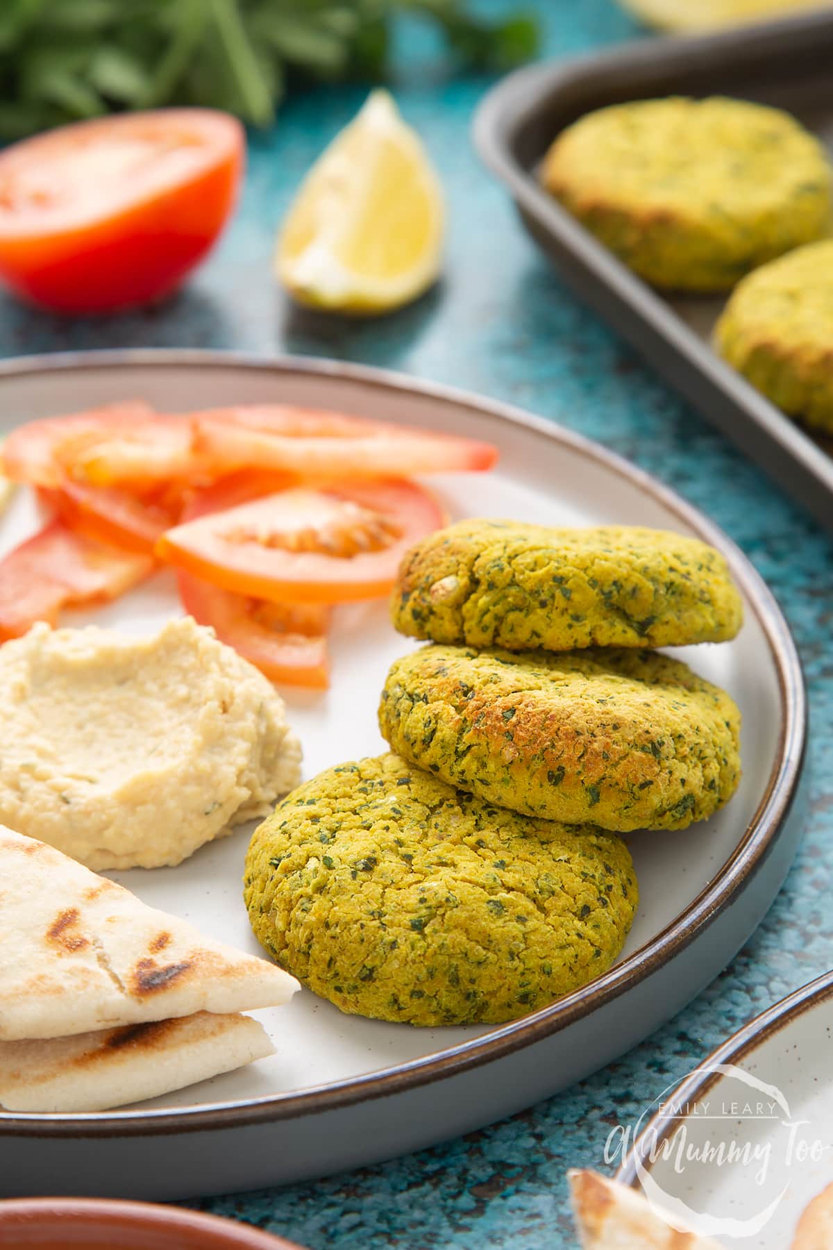 Gluten-free falafel arranged on a plate with tomatoes, cucumber, hummus and griddled flatbread.