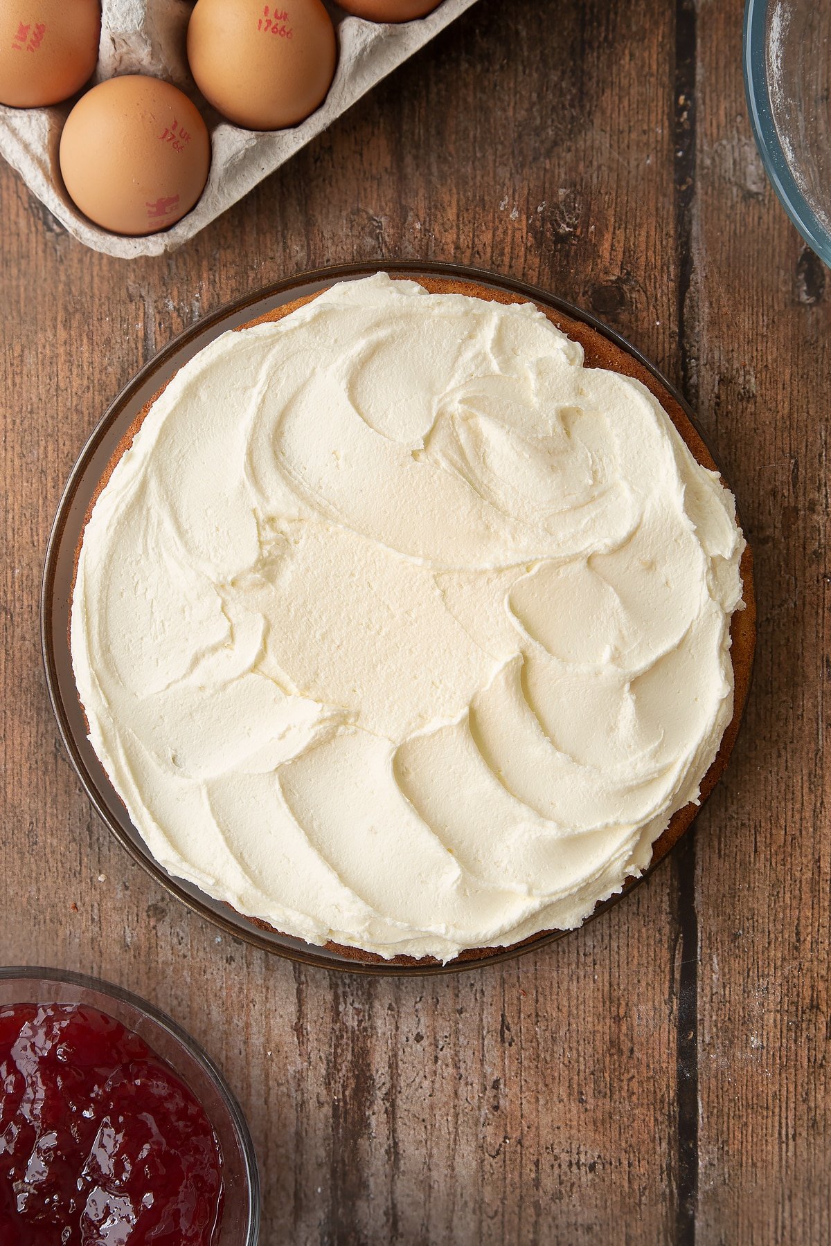 Overhead shot of Golden sponge cake covered in buttercream frosting on a wooden table. 