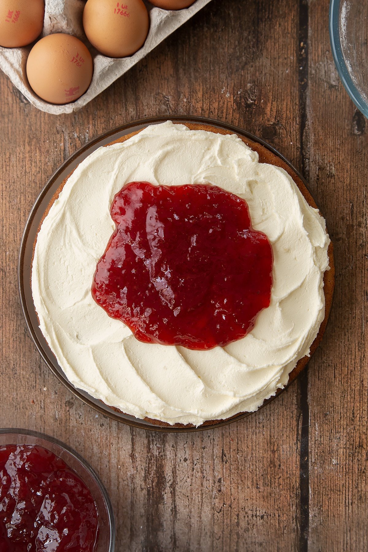 Adding jam on top of the buttercream frosting on the golden syrup sponge cake. 