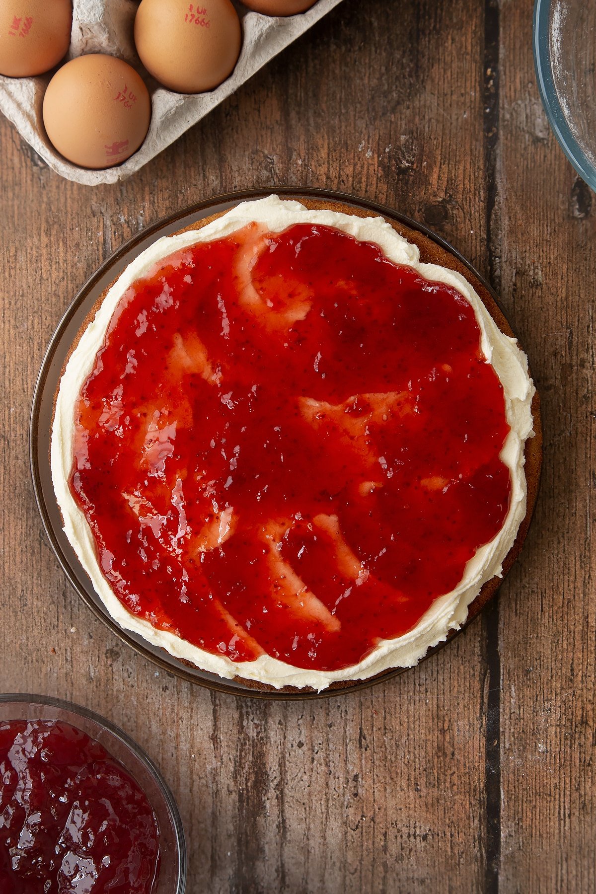 Overhead shot of the jam spread out on top of the golden syrup sponge cake. 