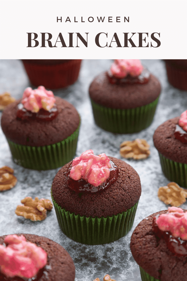 Gory Halloween cupcakes on a black background. The cupcakes are filled with jam and topped with pink candied walnuts that look like brains. Caption: Halloween brain cakes.