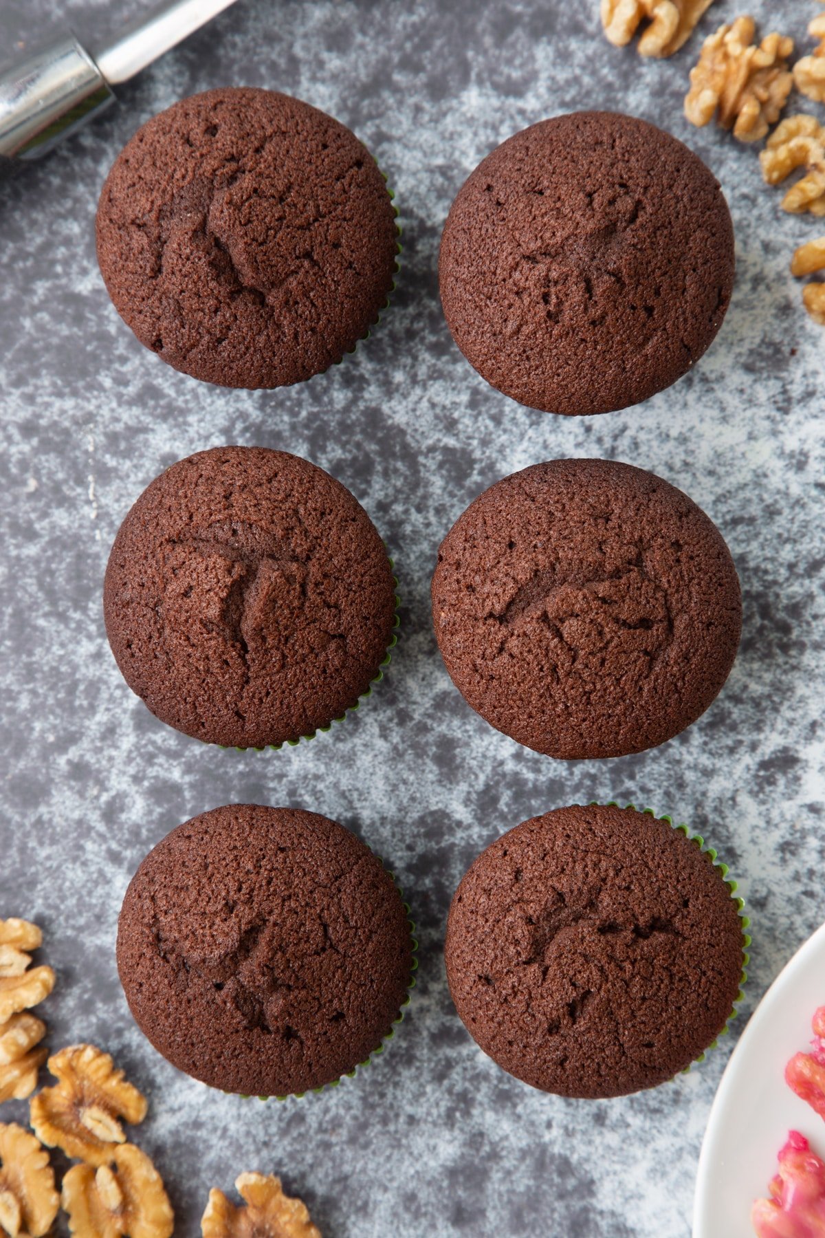 Six chocolate cupcakes. Ingredients to make gory Halloween cupcakes surround them.