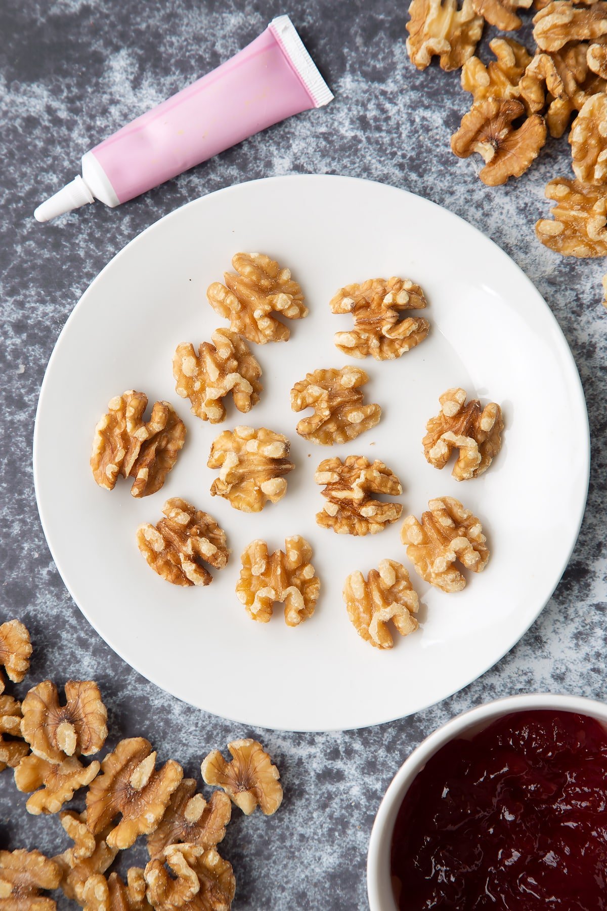 Walnuts on a white plate. Ingredients to make gory Halloween cupcakes surround them.
