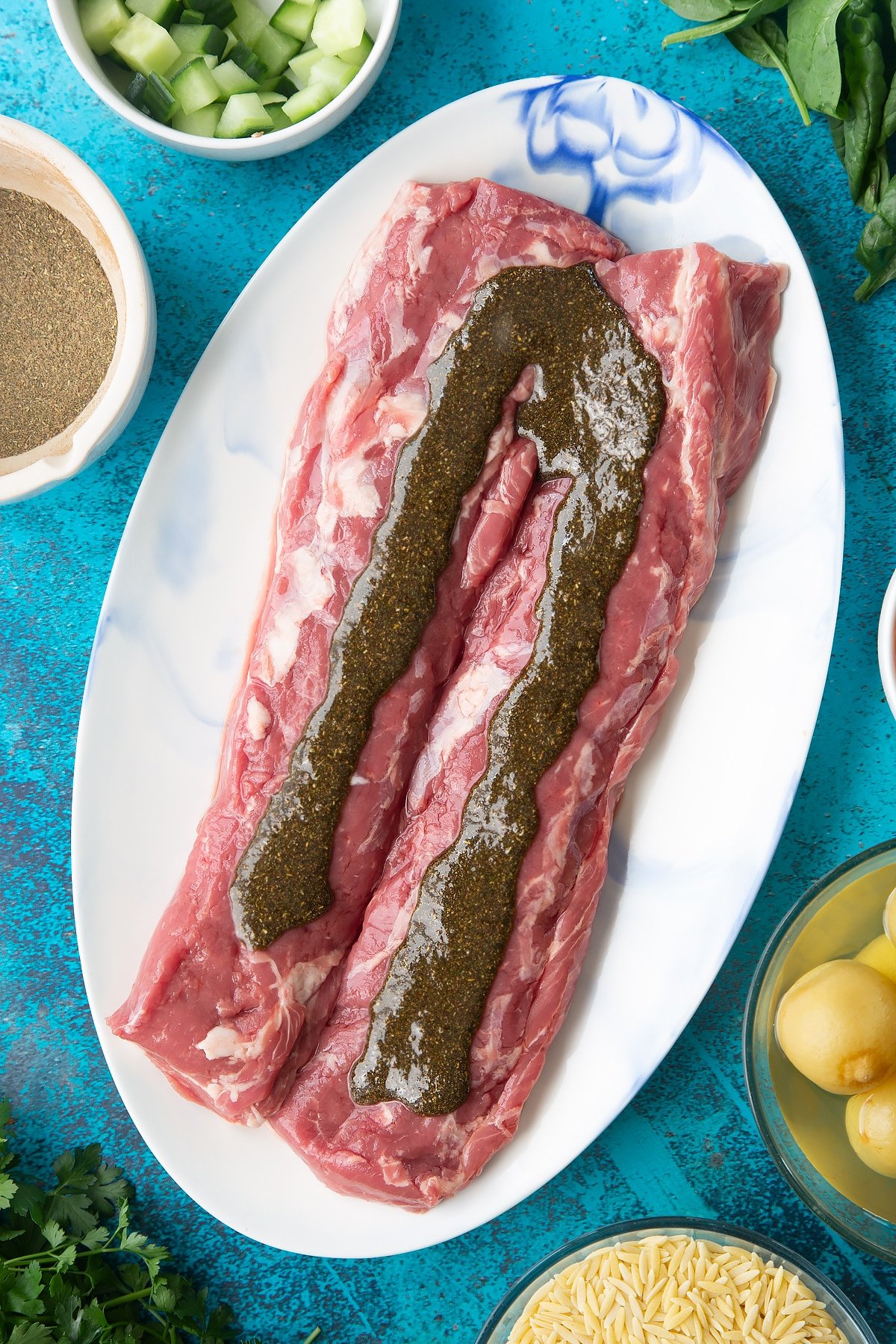 Two pieces of cannon of Welsh lamb on an oval platter. A herb and oil rub is drizzled on top.