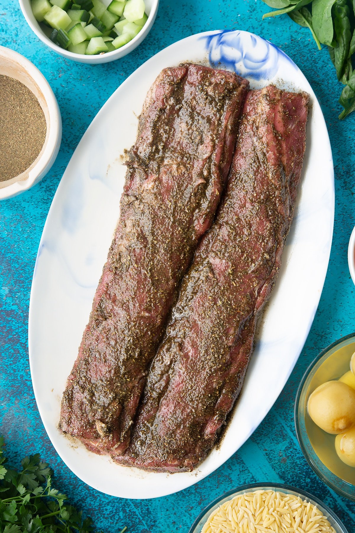 Two pieces of cannon of Welsh lamb covered with a herb and oil rub on an oval platter.