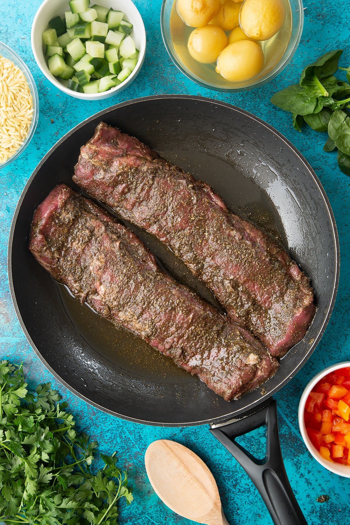 Two pieces of cannon of Welsh lamb covered with a herb and oil rub in a frying pan. 