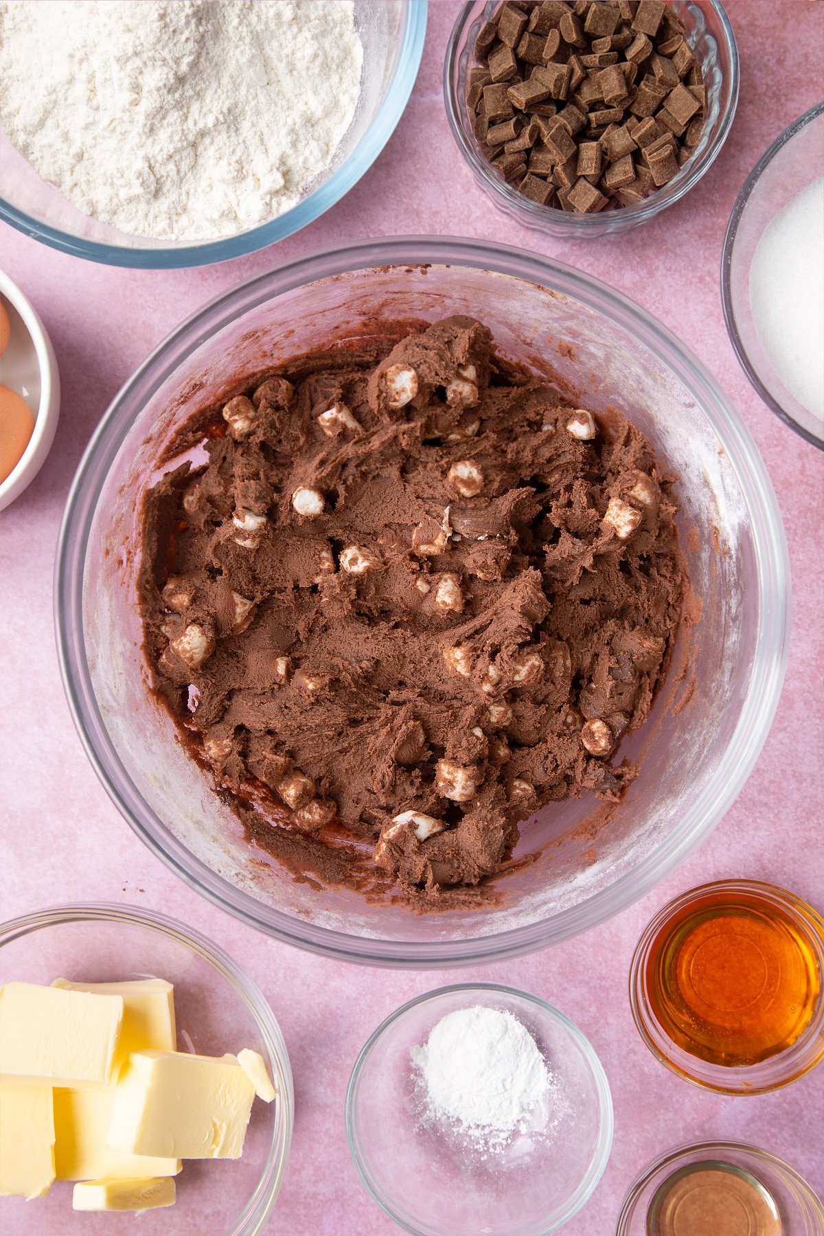 Overhead shot of mixed cookie dough with marshmellows in a large clear bowl