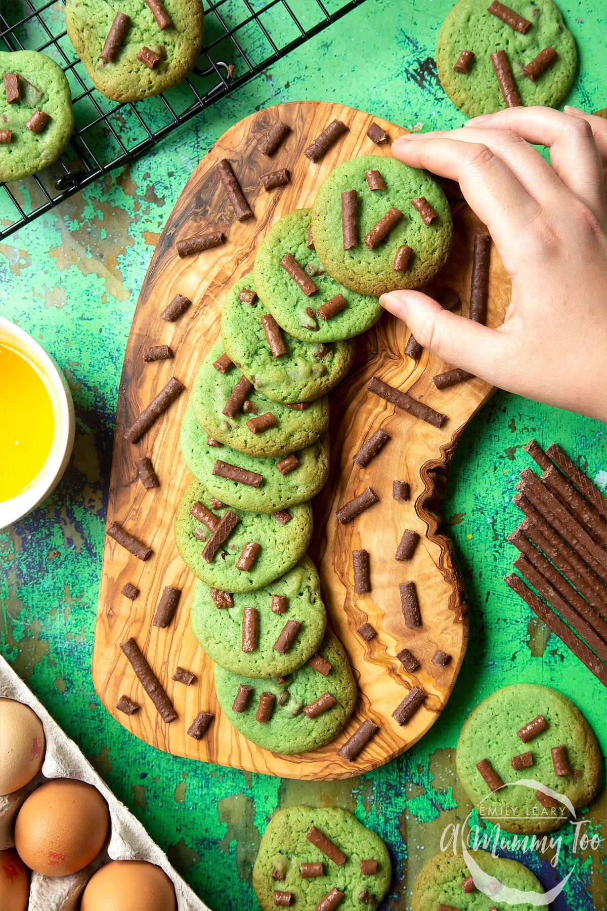 Matchmaker cookies arranged on a wooden board. A hand reaches to take a cookie.