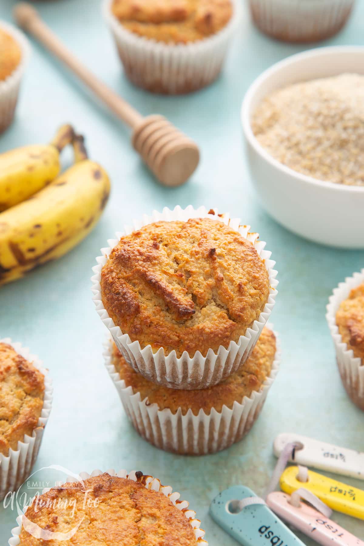  Front angle shot of stacked breakfast bran granola muffins with a mummy too logo in the lower-left corner