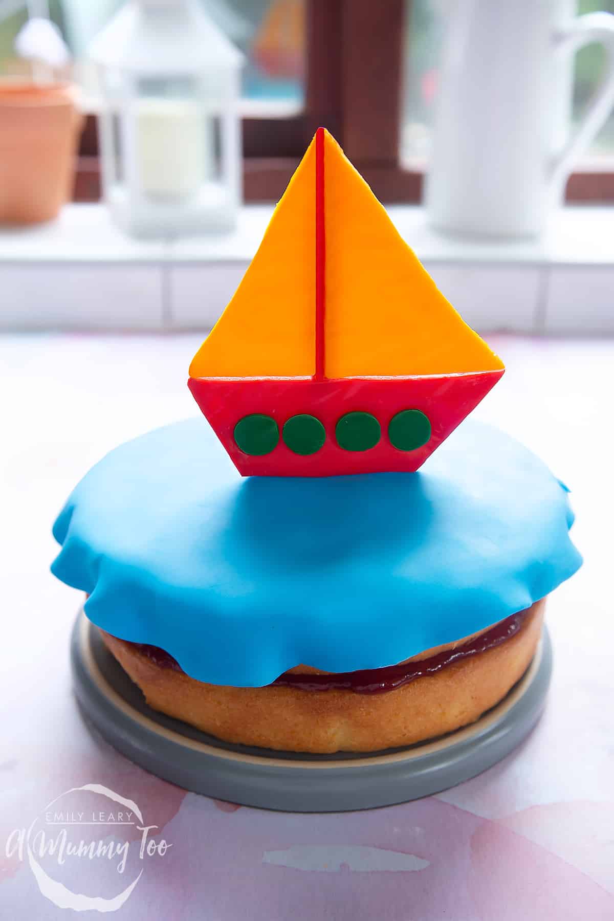 Front facing cake with a sugar paste sailing boat on the top.