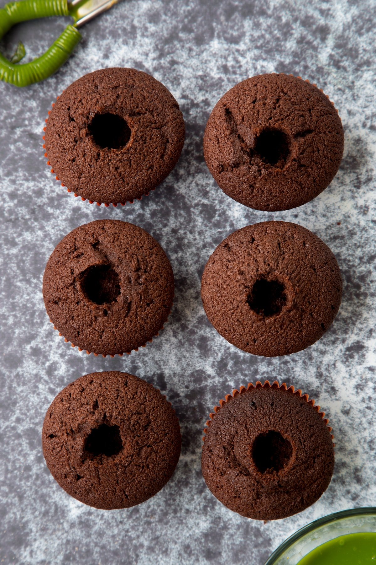 Six chocolate cupcakes shown from above. The cupcakes have their cores removed.