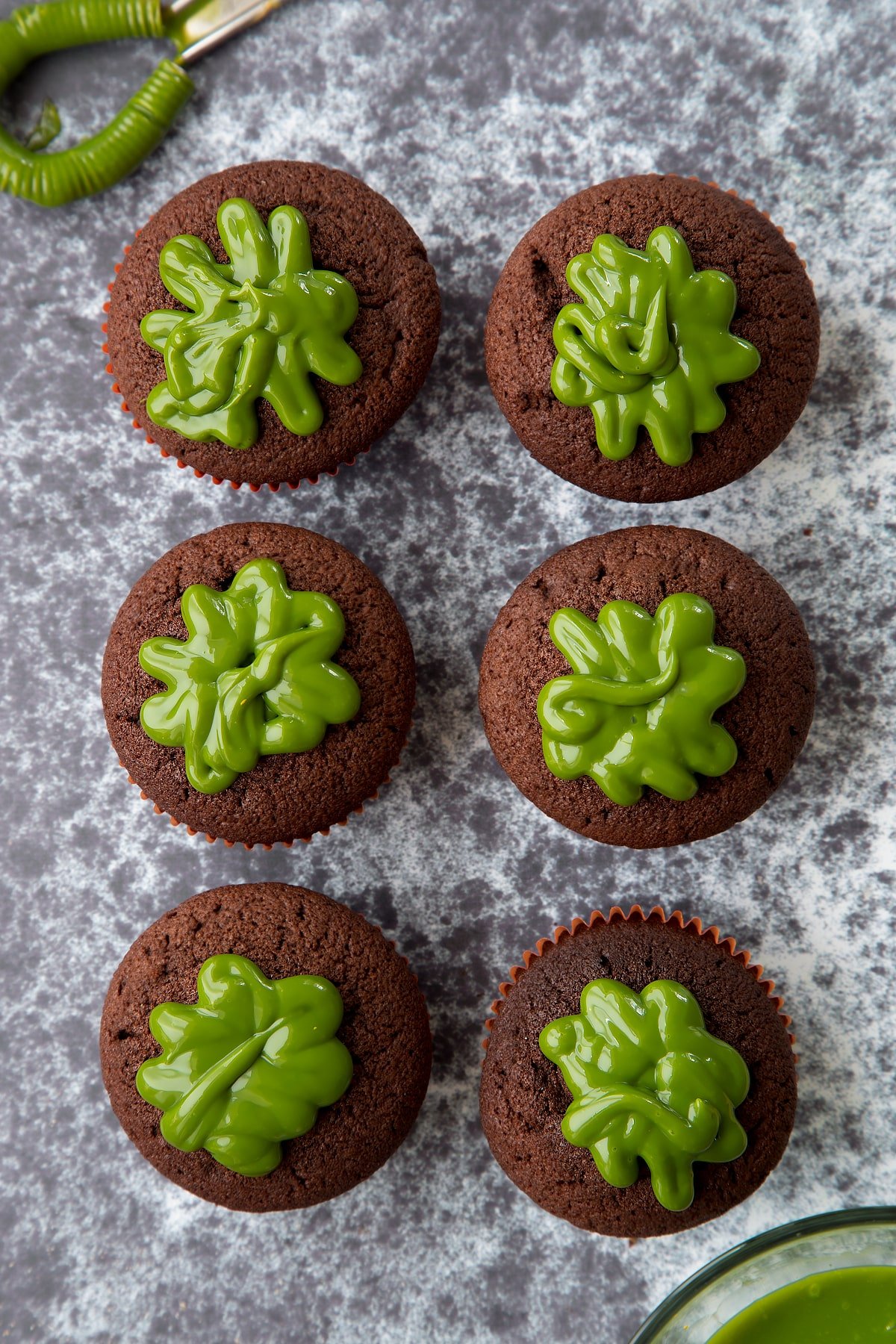 Six chocolate cupcakes shown from above. The cupcakes have been filled with dyed-green caramel. 