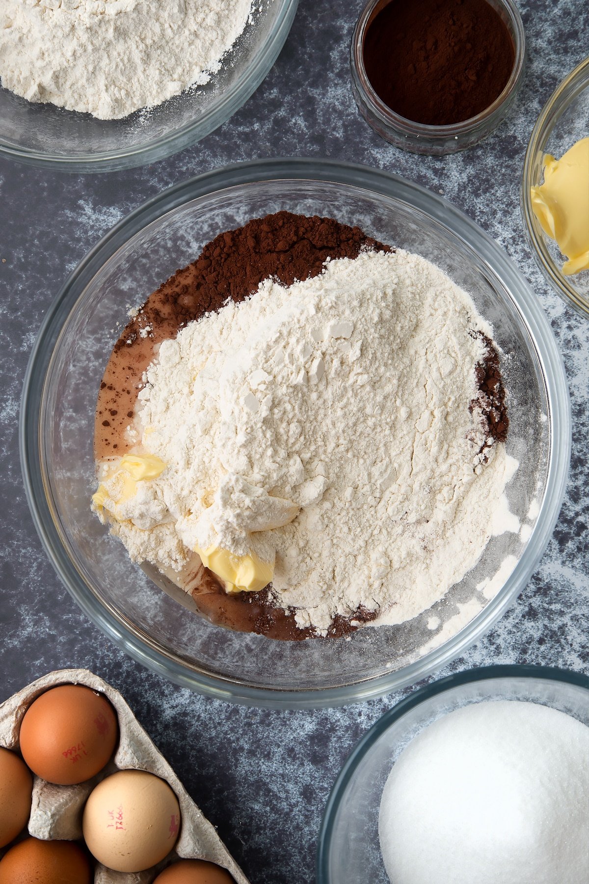 Margarine, sugar, eggs, vanilla, milk and self raising flour in a large mixing bowl. Ingredients to make spider web cupcakes surround the bowl.