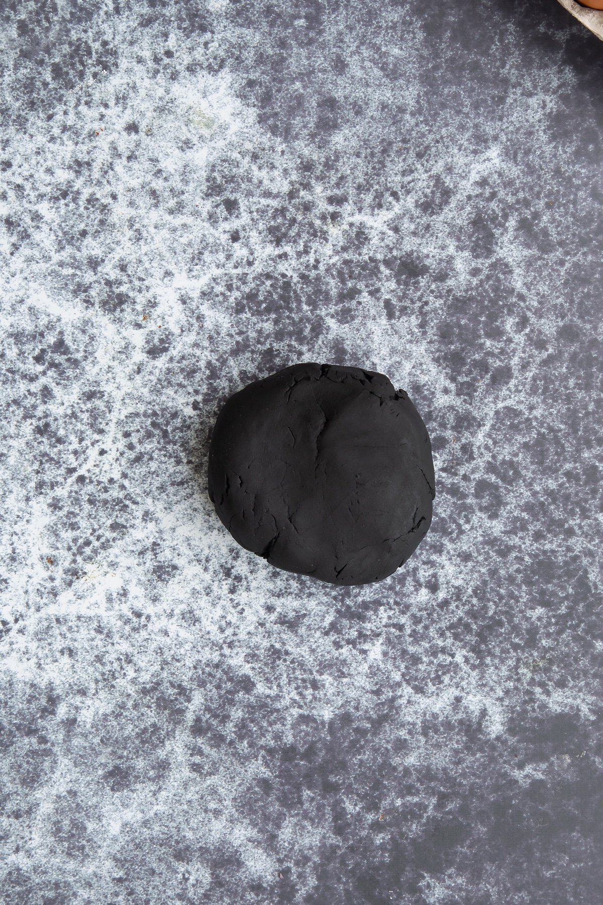 A ball of black sugar paste on a dark background.