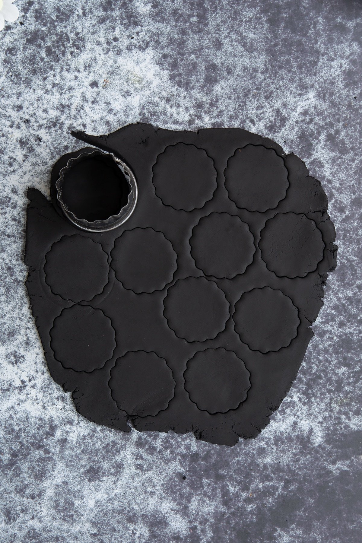 Discs of black sugar paste cut out on a dark background.