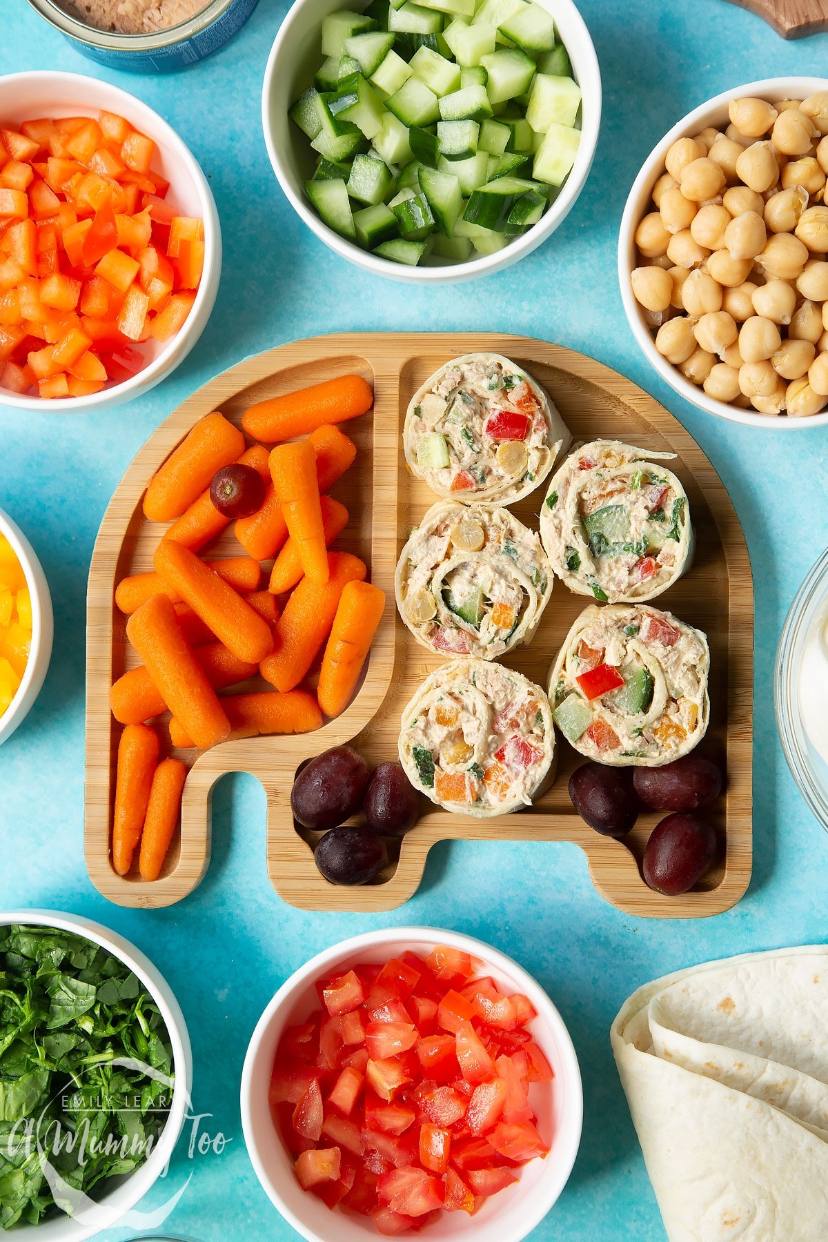 Tuna pinwheels served on a bamboo plate shaped like an elephant with fresh fruit and veg.