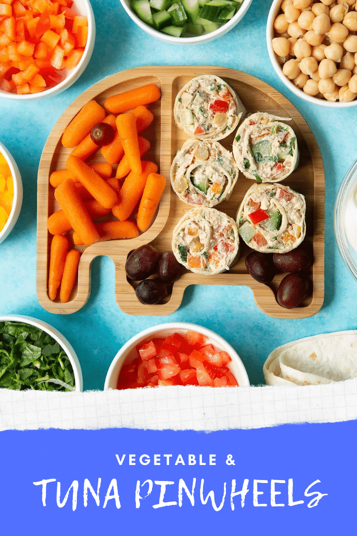 Tuna pinwheels on a bamboo plate with fresh fruit and veg. Caption reads: Vegetable & tuna pinwheels.