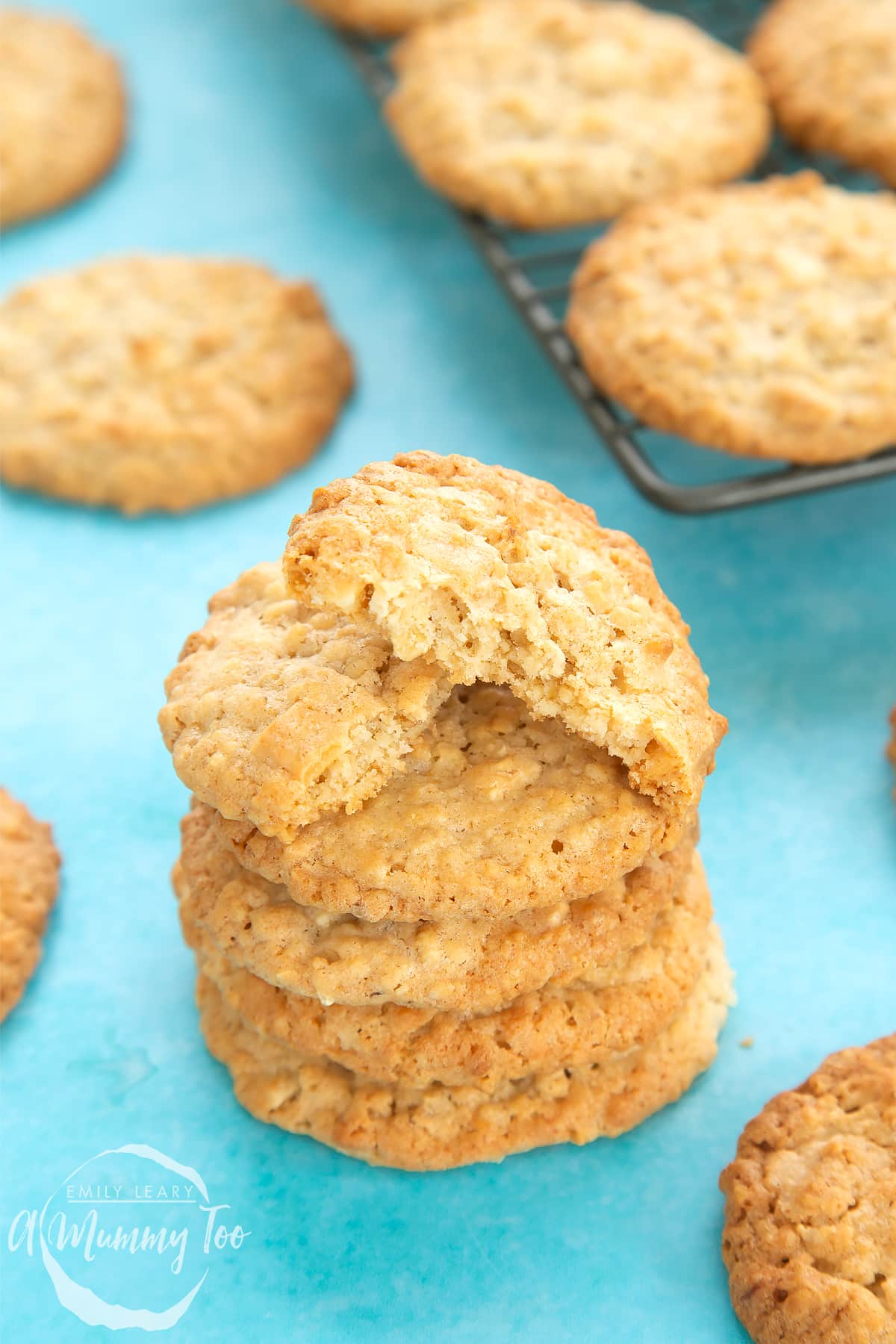 Front angle shot of stacked White chocolate chip oatmeal cookies with a mummy too logo in the lower-left corner