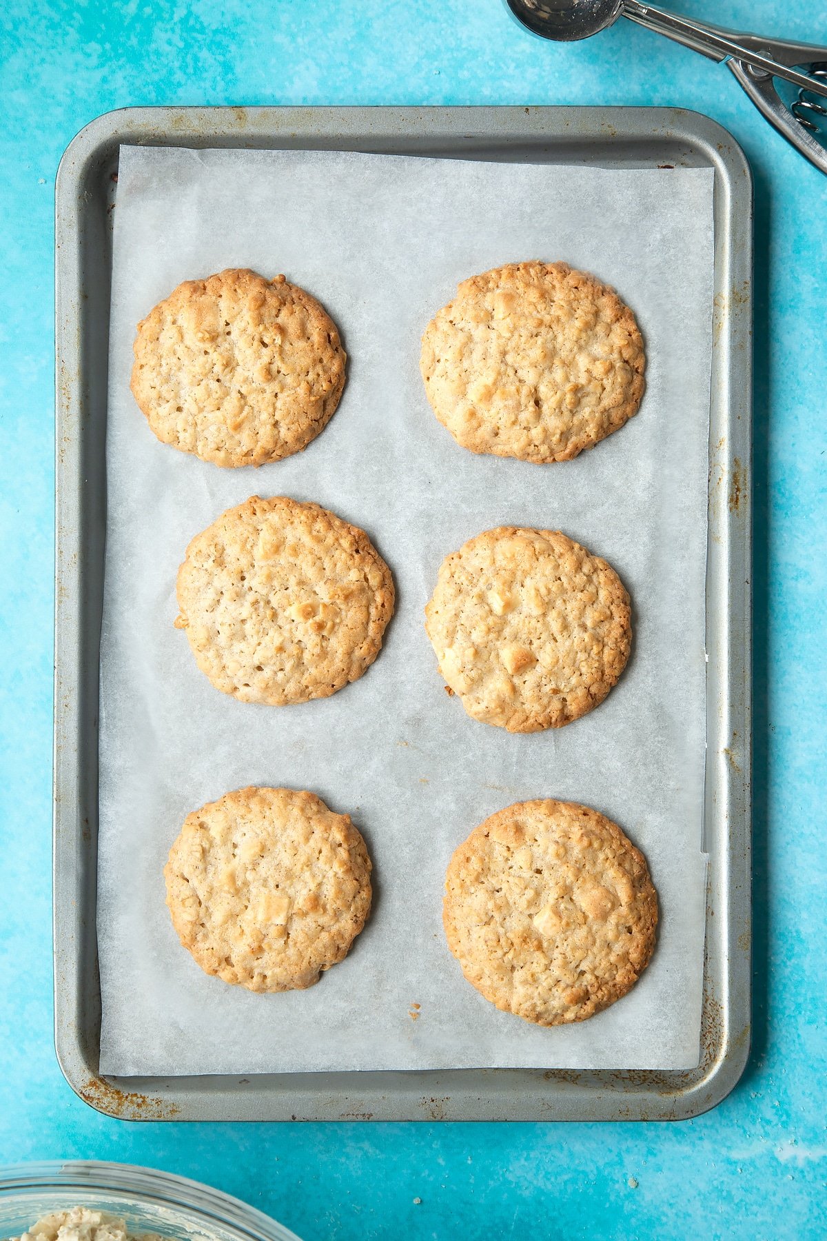 Overhead shot of white chocolate chip cookies baked on a baking tray lined with baking paper