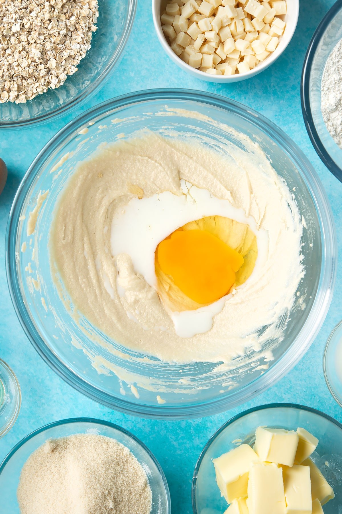 Overhead shot of butter mix, milk, eggs and vanilla extract in a large clear bowl