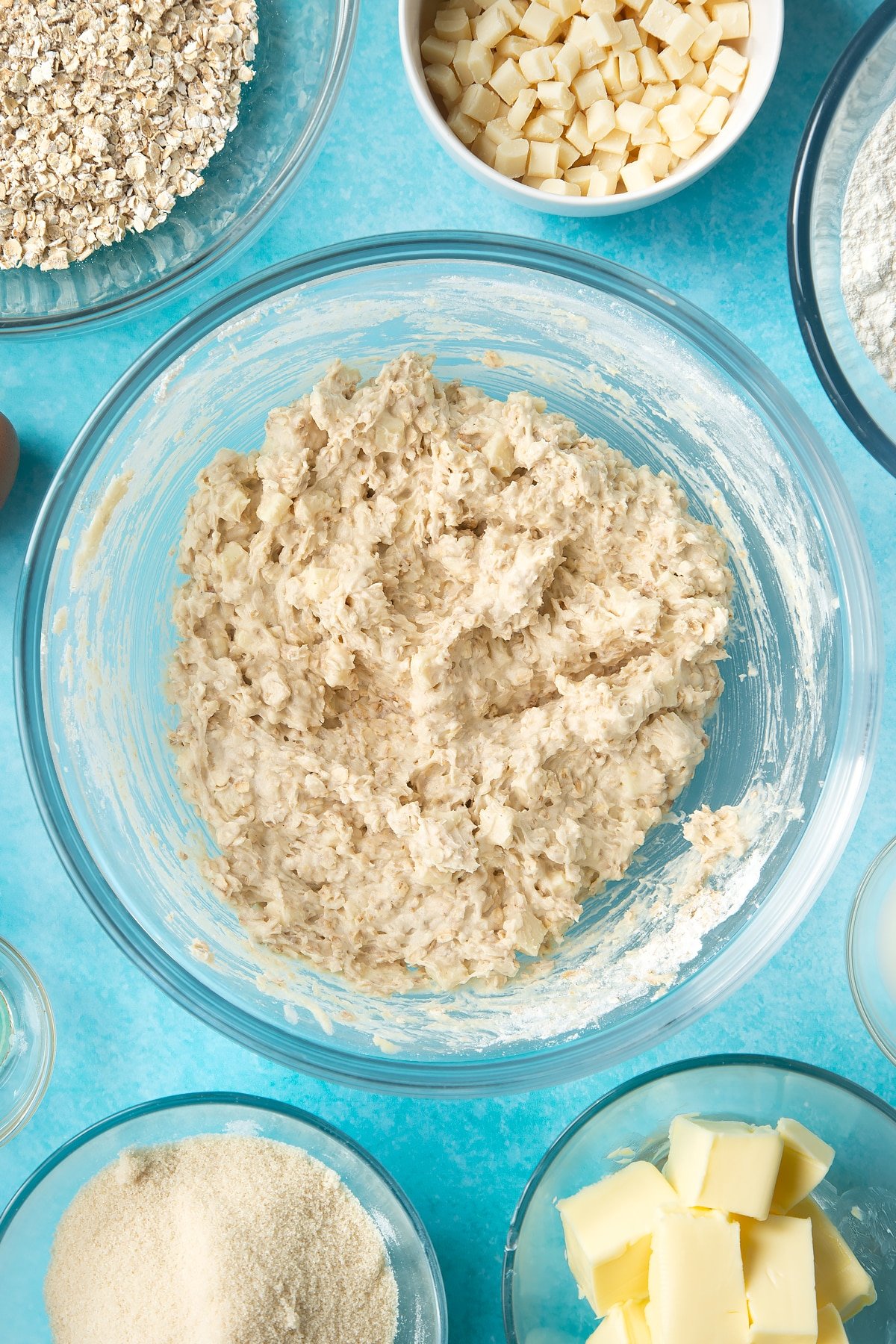 Overhead shot of mixed dough of white chocolate chip oatmeal cookies in a large clear bowl