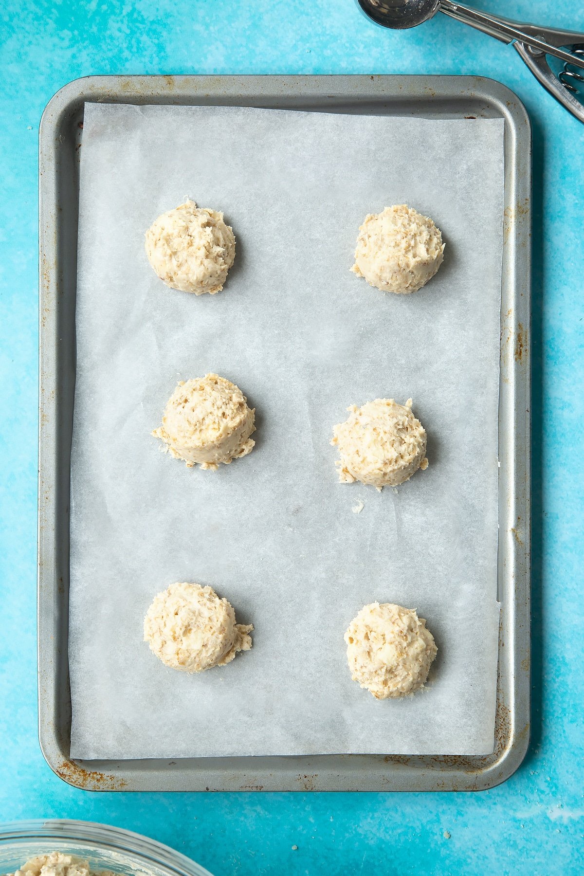 Overhead shot of white chocolate chip oatmeal cookie dough balls on a lined baking tray