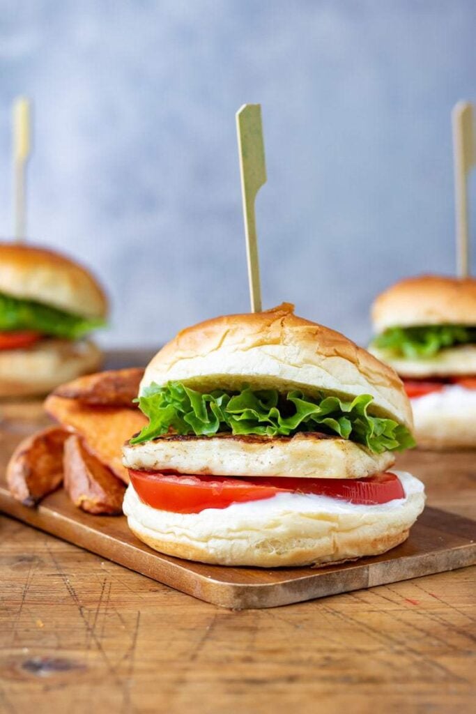 Cajun halloumi burger sat on a wooden serving board with a side of potato fries.