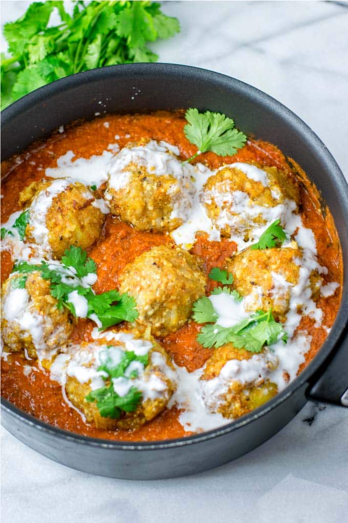 Bowl of Malia Kofta on a white grafite background topped with parsley. 