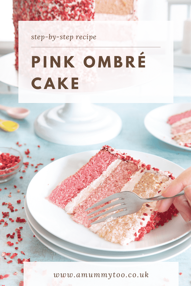 A slice of pink ombre cake on a stack of small white plates. The cake has three layers, each an increasingly intense shade of pink. The sponges are layered with pale pink frosting and the outside is decorated with freeze dried strawberry pieces. A hand holds a fork which is delving into the cake slice. Caption reads: Step-by-step recipe pink ombre cake