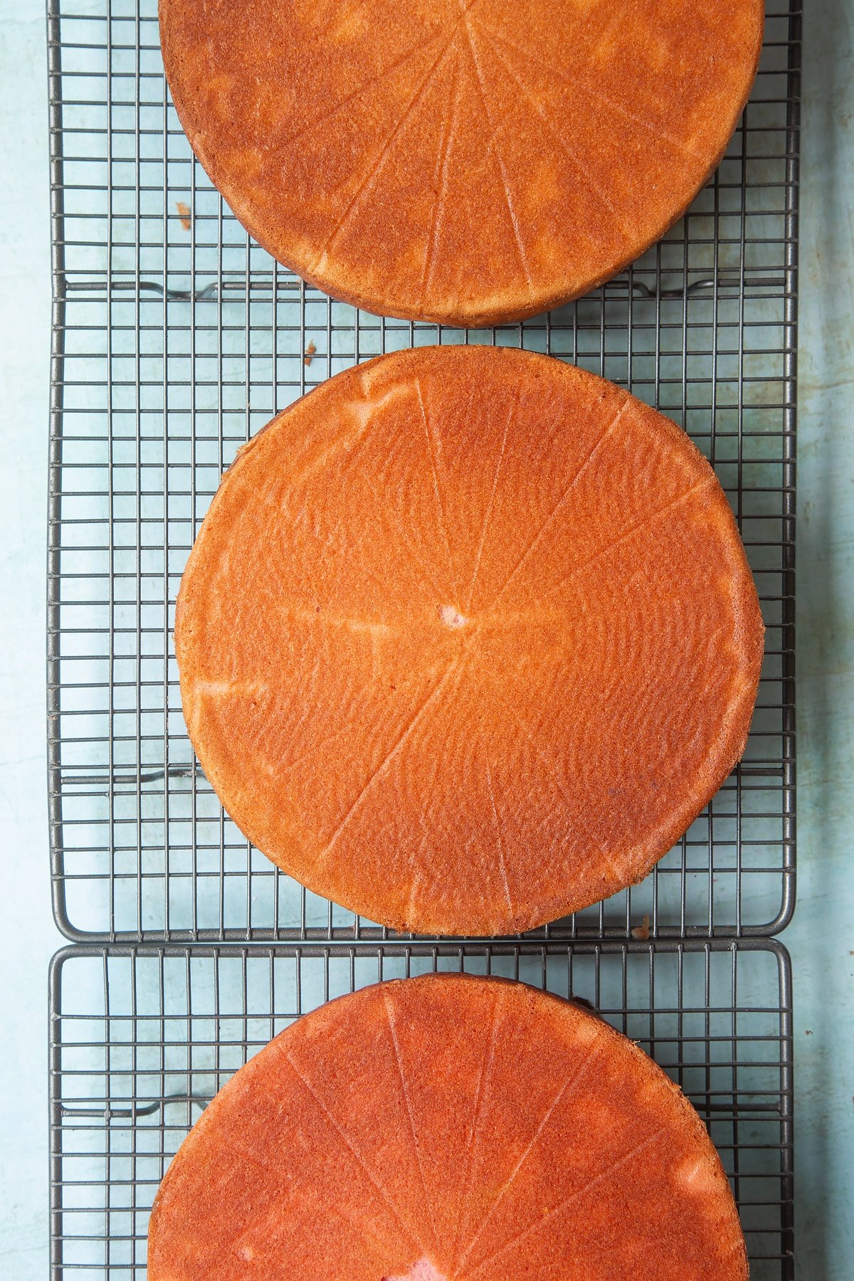 Three cakes cooling on a wire rack.