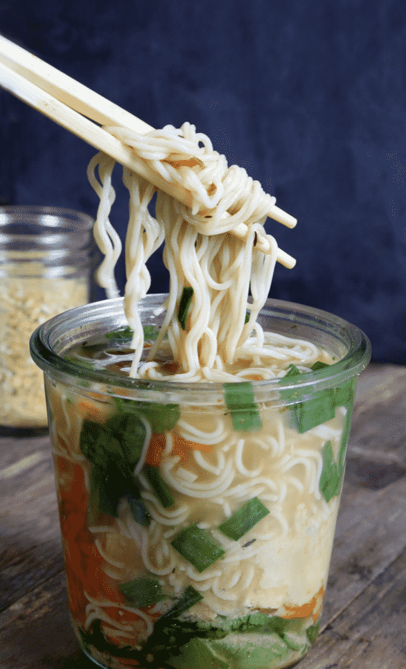 Large bowl of noodles, some of which are being picked up with a pair of chopsticks ready to be eaten.