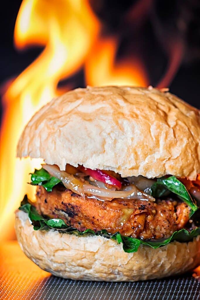 Spicy bean burger on a black placemat with a flame in the background.