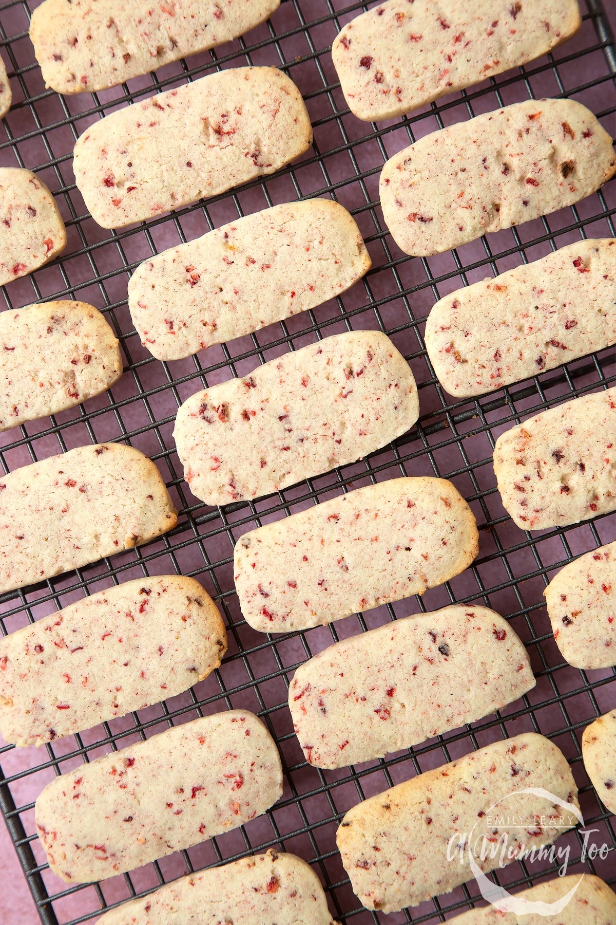 Close up of strawberry biscuits on a wire rack having been in the oven. 
