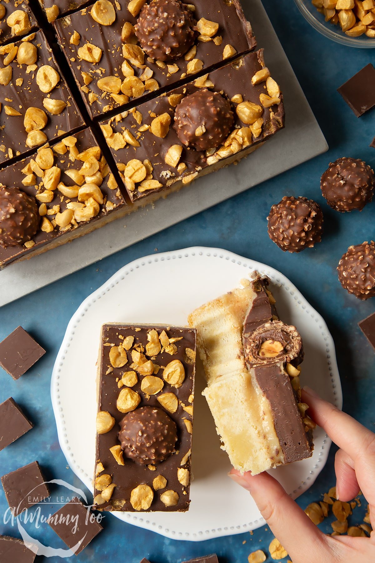 Two Ferrero Rocher slices on a plate. One is turned on its side and has a bite out of it. A hand reaches for it.