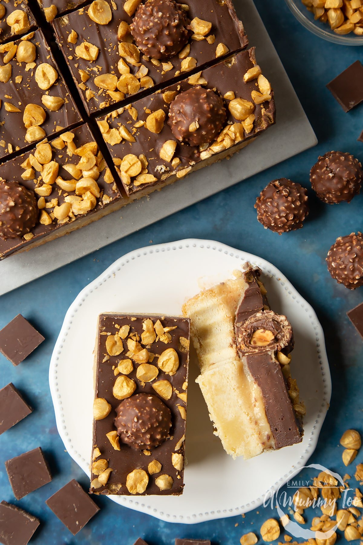 Two Ferrero Rocher slices on a plate. One is turned on its side and has a bite out of it. To the side is a tray with more slices.