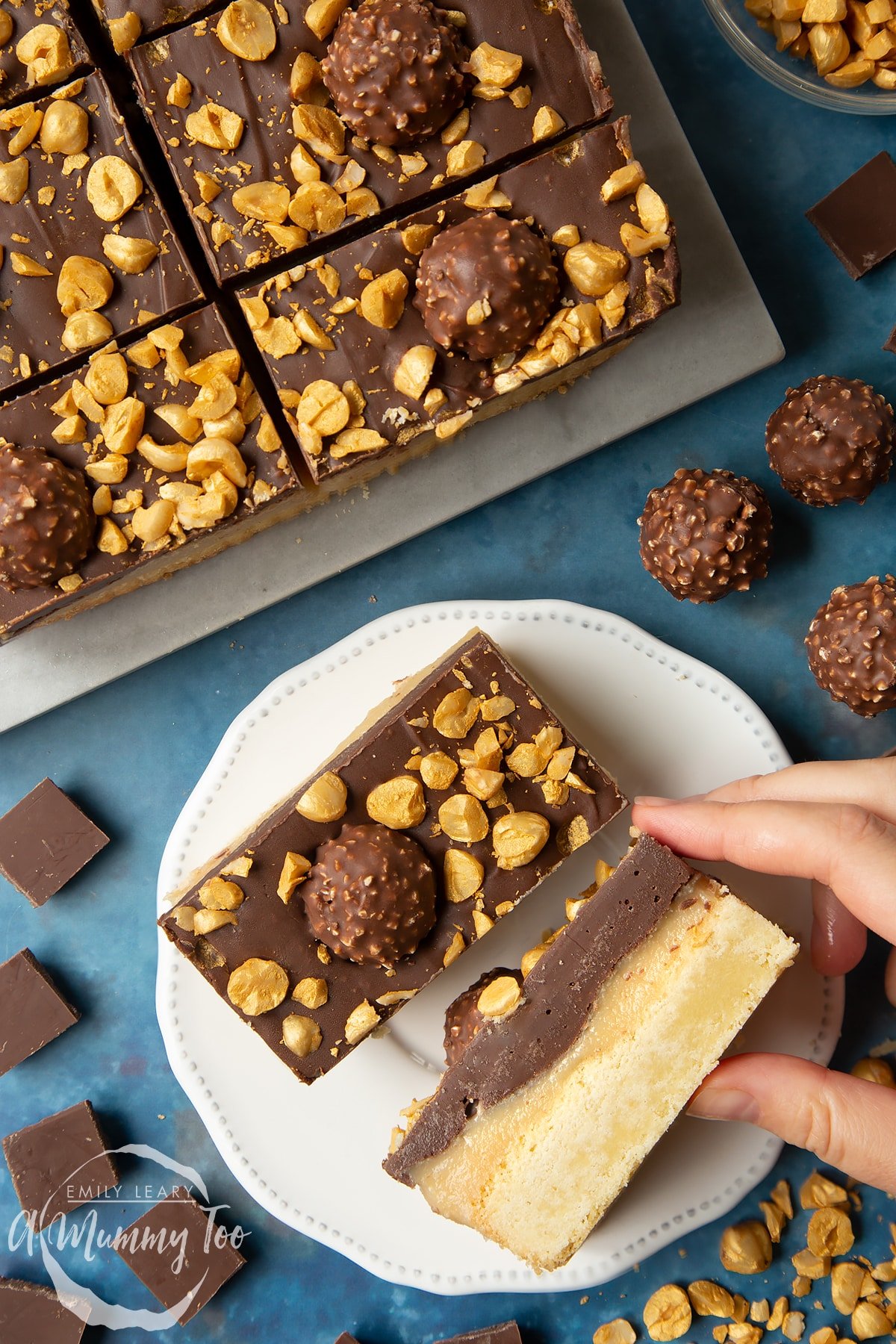 Two Ferrero Rocher slices on a plate. One is turned on its side - a hand reaches for it. To the side is a tray with more slices.