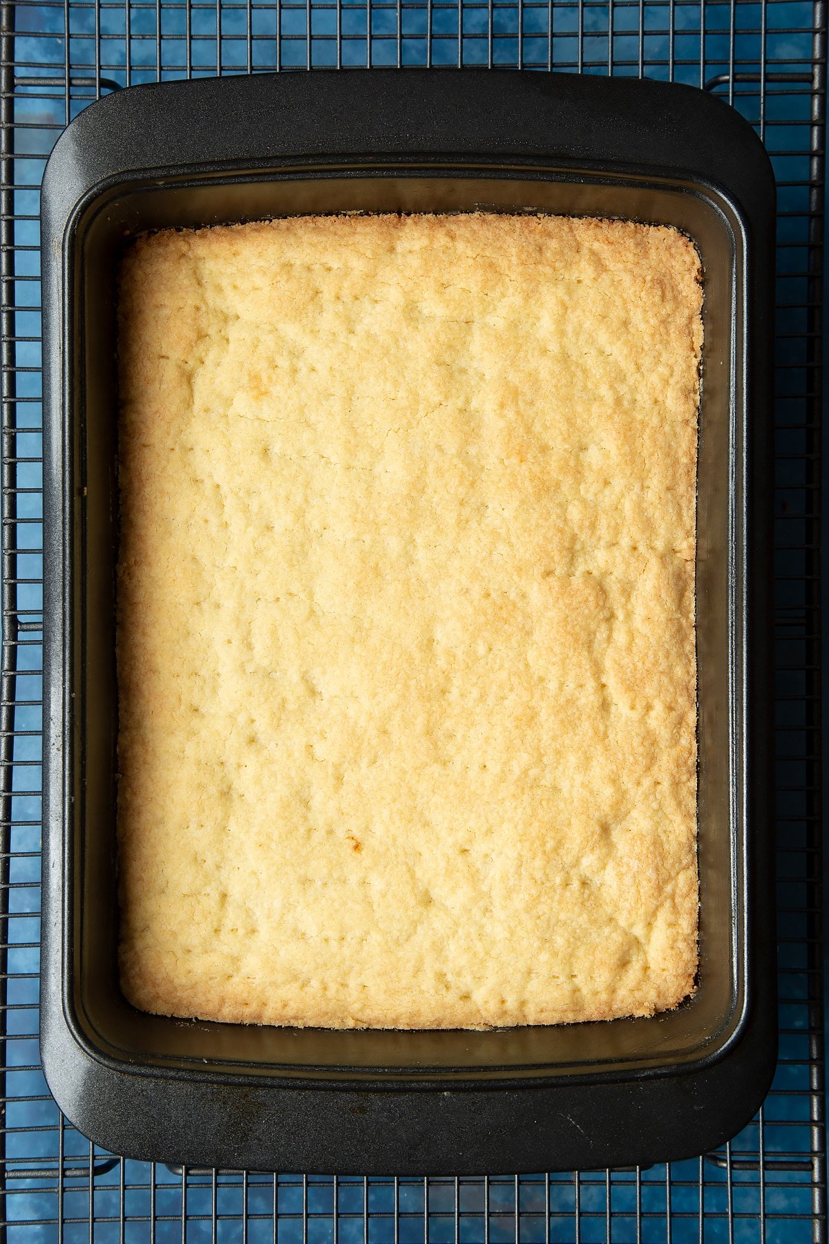 Cooked shortbread in a tray on a cooling rack.