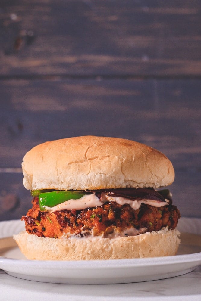 An American style kidney bean burger on a white plate with a blue background.