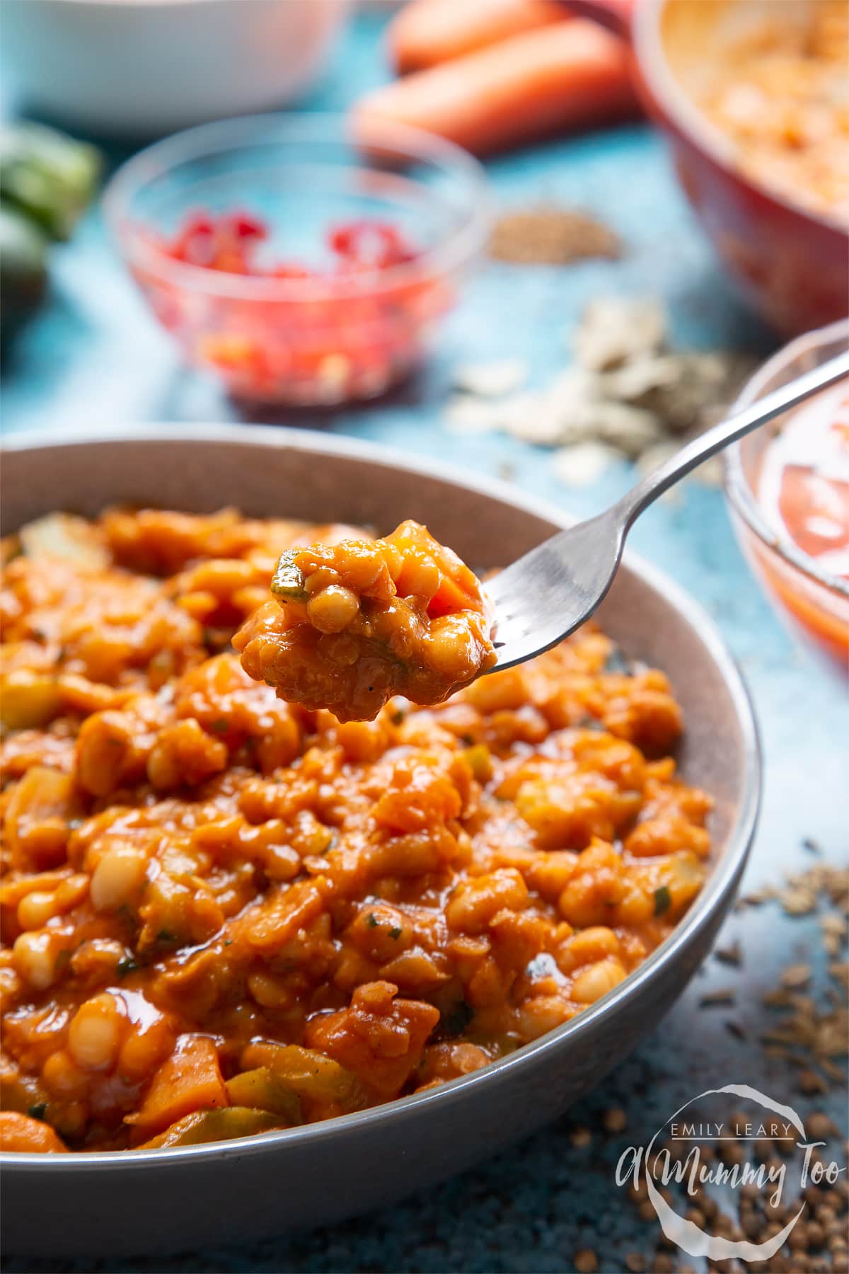 Baked bean curry served in a grey bowl. A fork dips into the curry.
