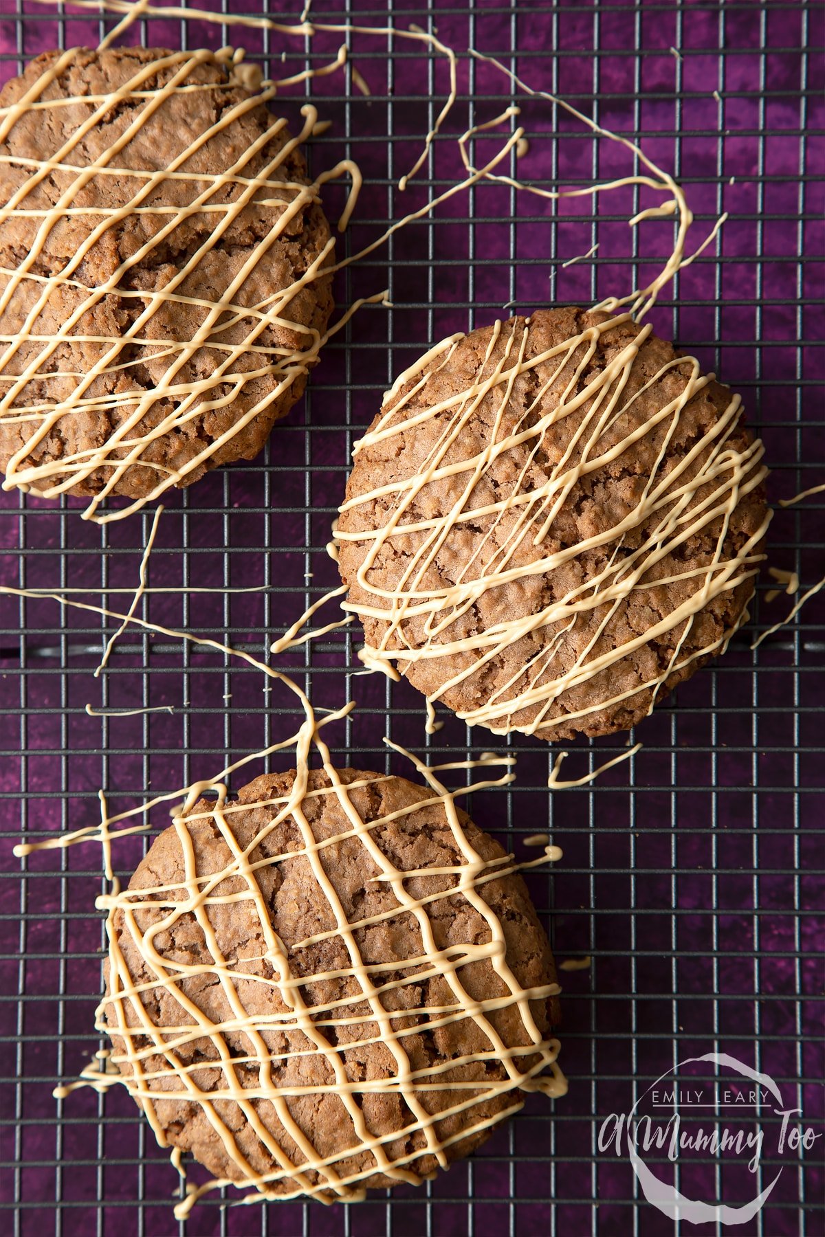 Three freshly decorated Ferrero Rocher cookies on a cooling rack.