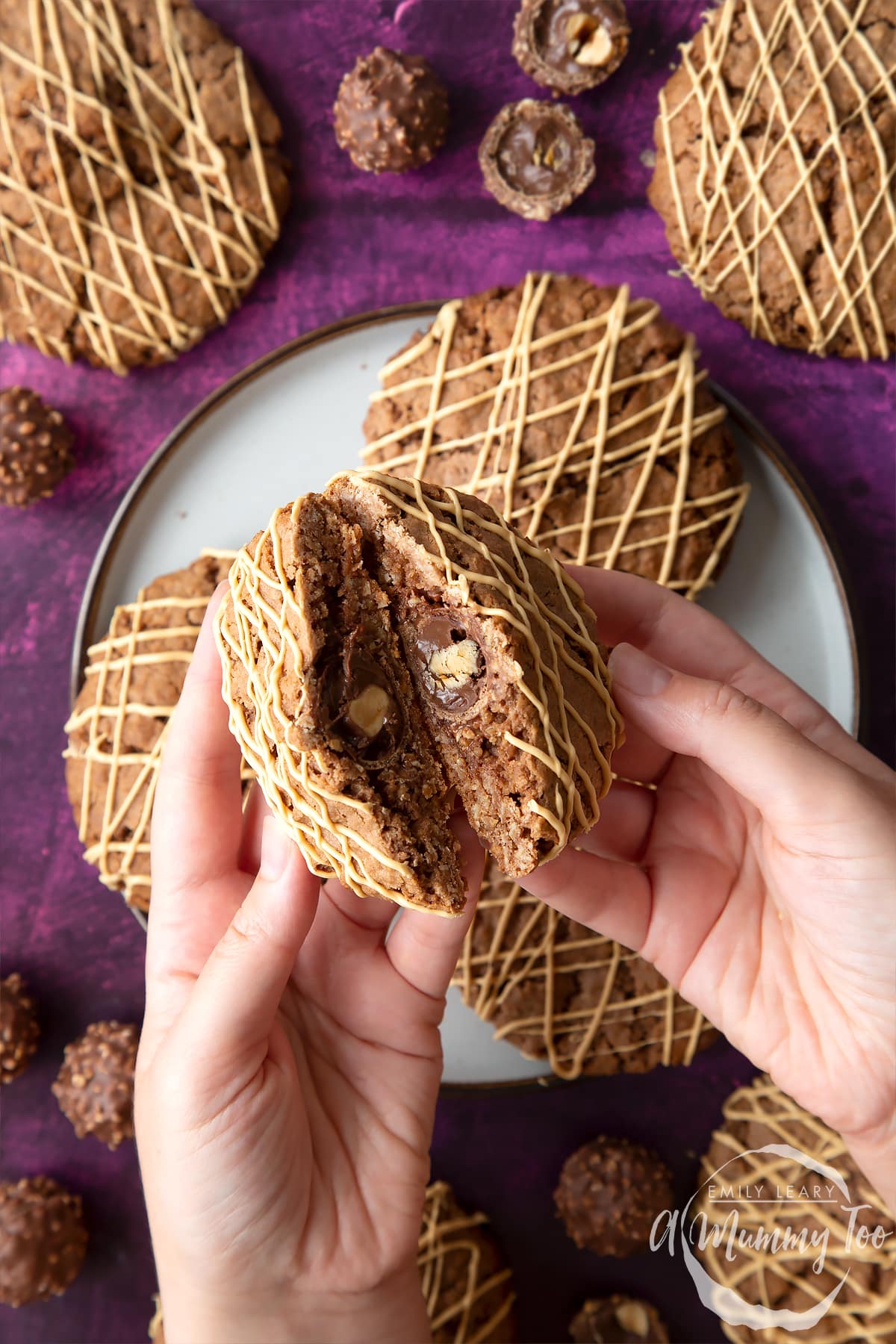 Ferrero Rocher cookies on a plate. Hands hold one, which has been cut in half to reveal the whole Ferrero Rocher in the centre.