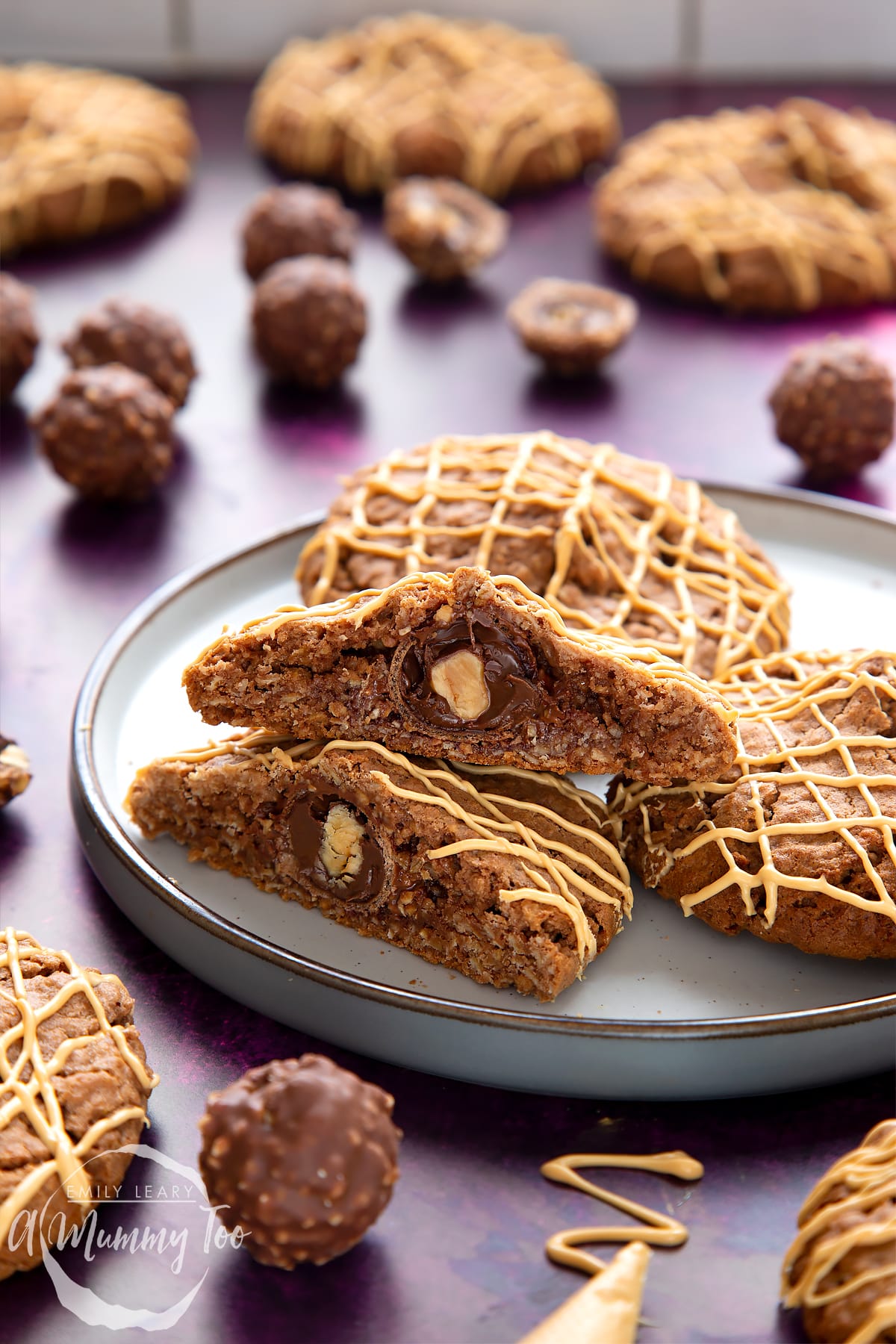 Ferrero Rocher cookies on a plate. One has been cut in half, revealing the whole Ferrero Rocher in the centre.