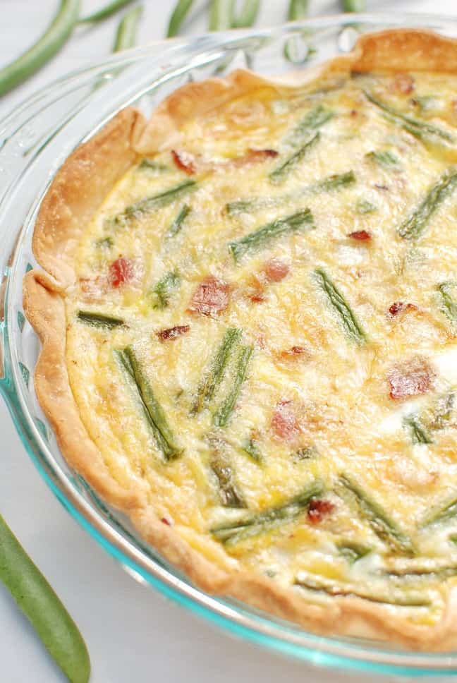 A whole Green Bean Quiche in a pyrex dish on a white background.